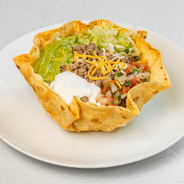 Muchas Gracias Mexican Food's taco salad in a crispy tortilla bowl with ground beef, guacamole, and sour cream.