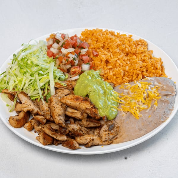 Muchas Gracias Mexican Food's chicken fajita plate with rice, beans, guacamole, pico de gallo, and lettuce.