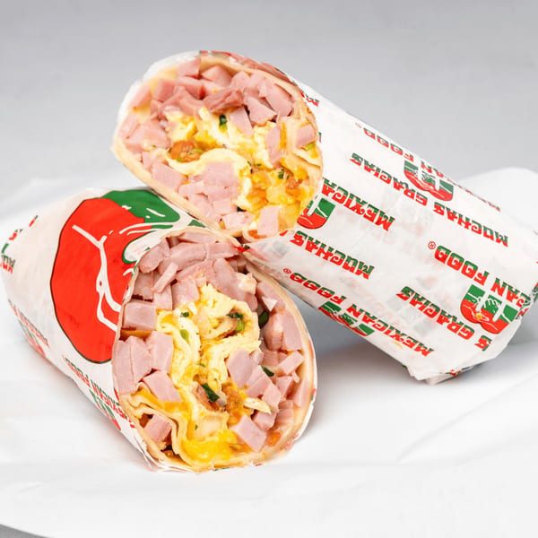 Two Muchas Gracias Mexican Food breakfast burritos, cut in half, filled with ham and scrambled eggs.