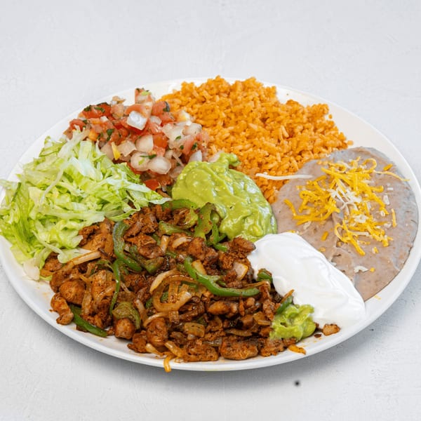 A Muchas Gracias Mexican Food plate with fajita chicken, rice, beans, guacamole, sour cream, pico de gallo, and lettuce.