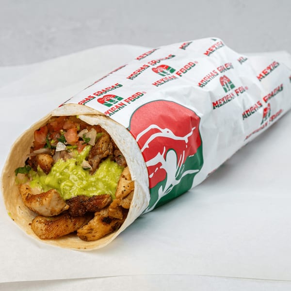 A Muchas Gracias Mexican Food burrito, unwrapped to show grilled chicken, guacamole, and pico de gallo.
