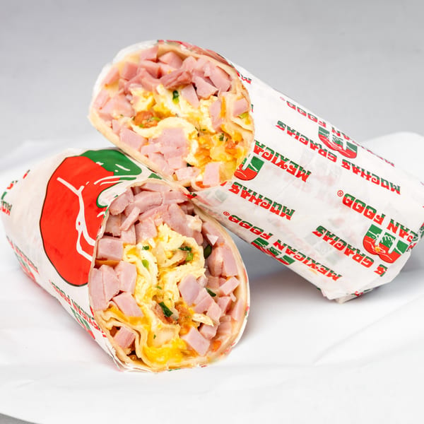 Two Muchas Gracias Mexican Food breakfast burritos, cut in half, revealing ham, scrambled eggs, and cheese.