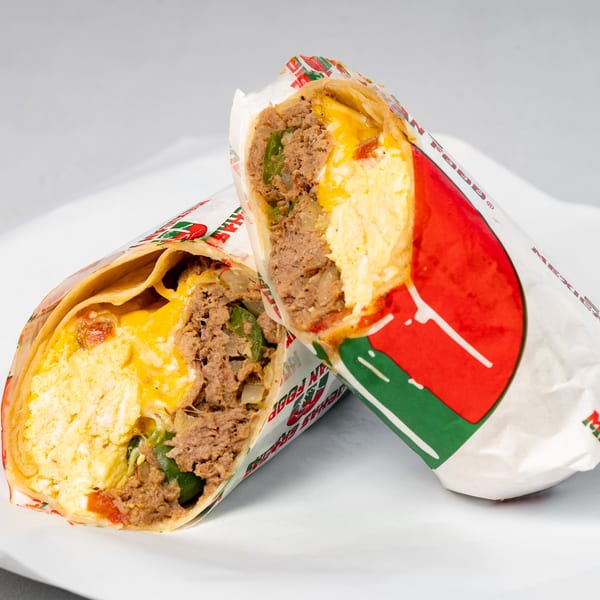 Two halves of a Muchas Gracias Mexican Food breakfast burrito, filled with eggs, meat, and cheese.