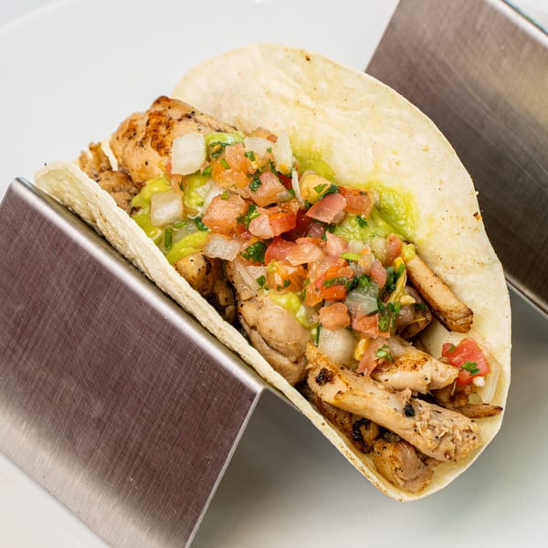 A chicken taco from Muchas Gracias Mexican Food, filled with grilled chicken, guacamole, and pico de gallo.