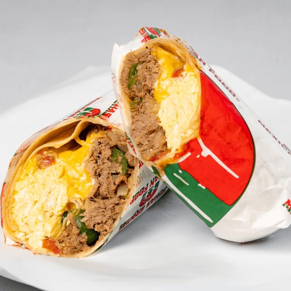 Two halves of a Muchas Gracias Mexican Food breakfast burrito, filled with eggs, cheese, and meat.
