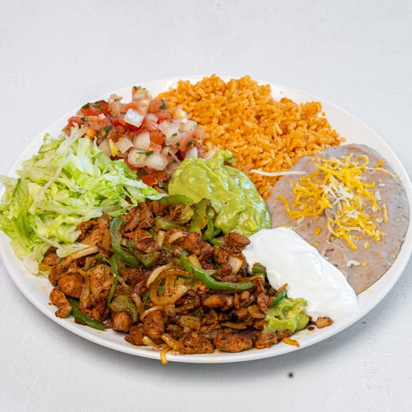 A Mexican food plate with chicken fajitas, rice, refried beans, guacamole, sour cream, pico de gallo, and lettuce.